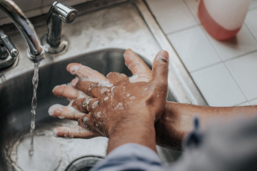 Photo of a man washing his hands with soap at the kitchen sink