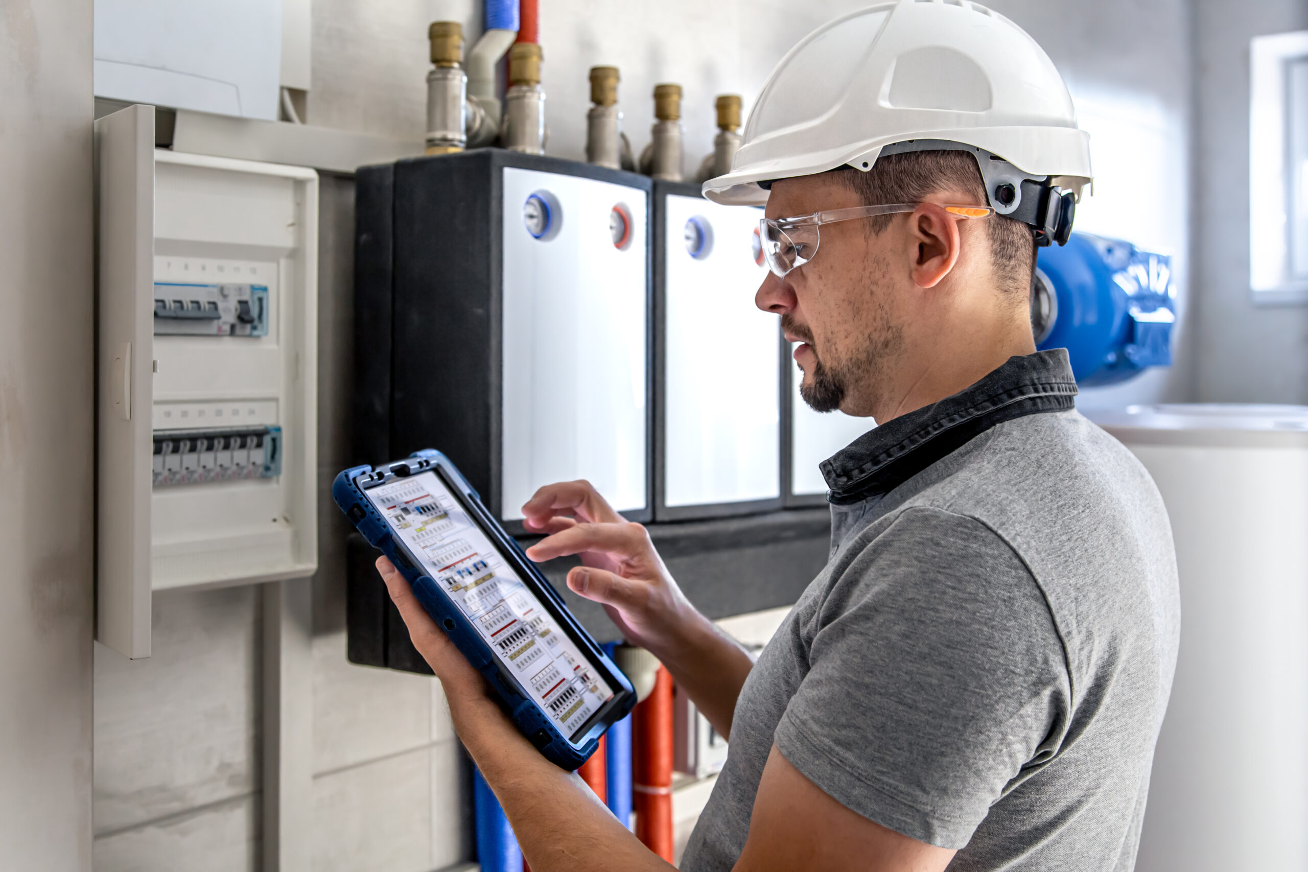 Electrical technician looking focused while working in a switchboard with fuses.