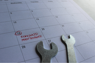 Photo of a calendar showing scheduled maintenance on the 19th of the month. On top of the calendar rests 2 spanners.