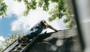Man on stepladder on roof of property carrying out safety inspection
